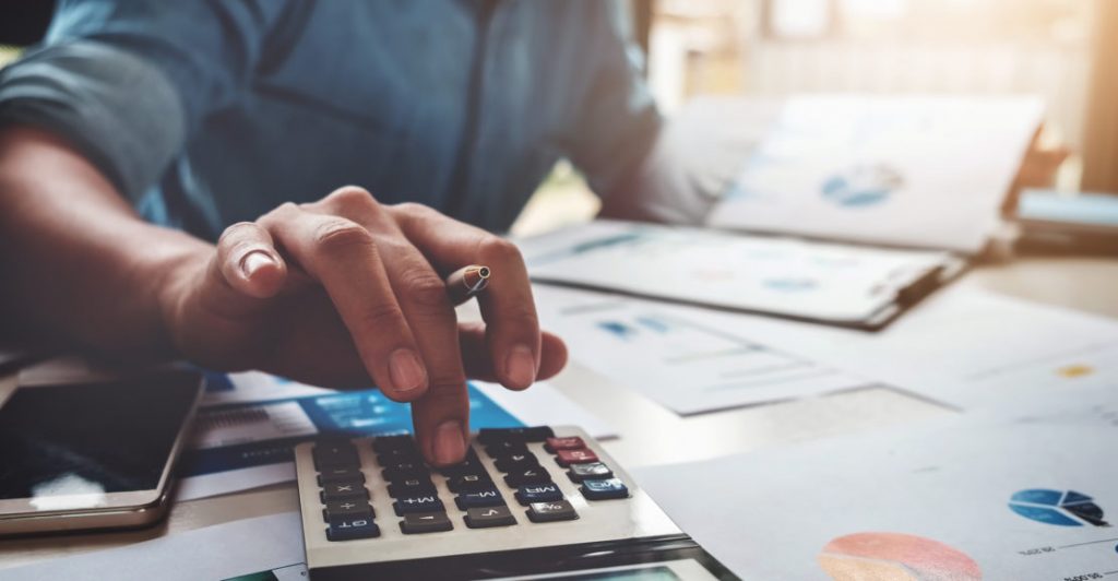 Business accounting concept, Business man using calculator with computer laptop, budget and loan paper in office.